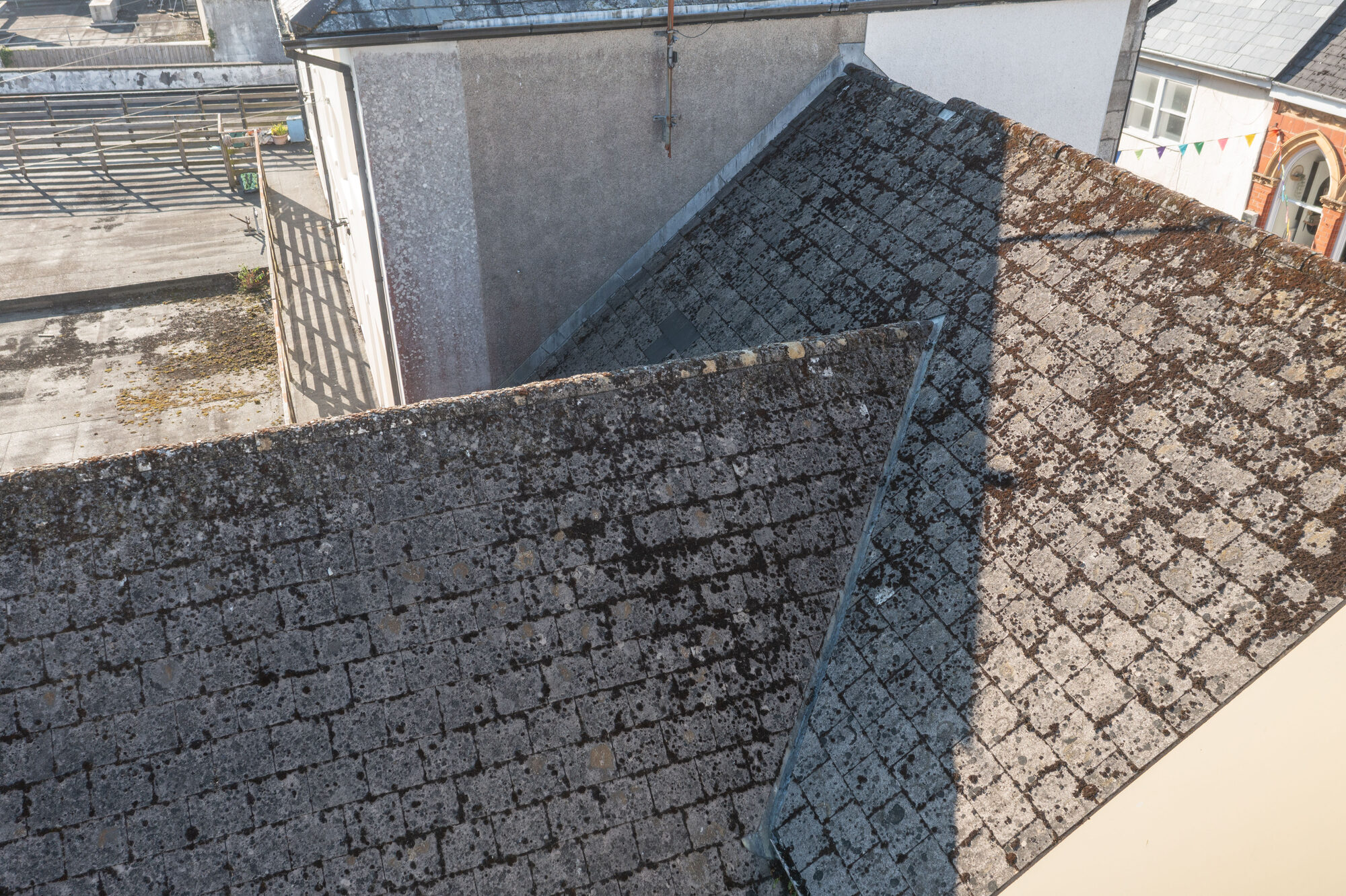 Drone photo of two slate roofs meeting, showing the lead work along the join, on a building on Fore Street, Bodmin