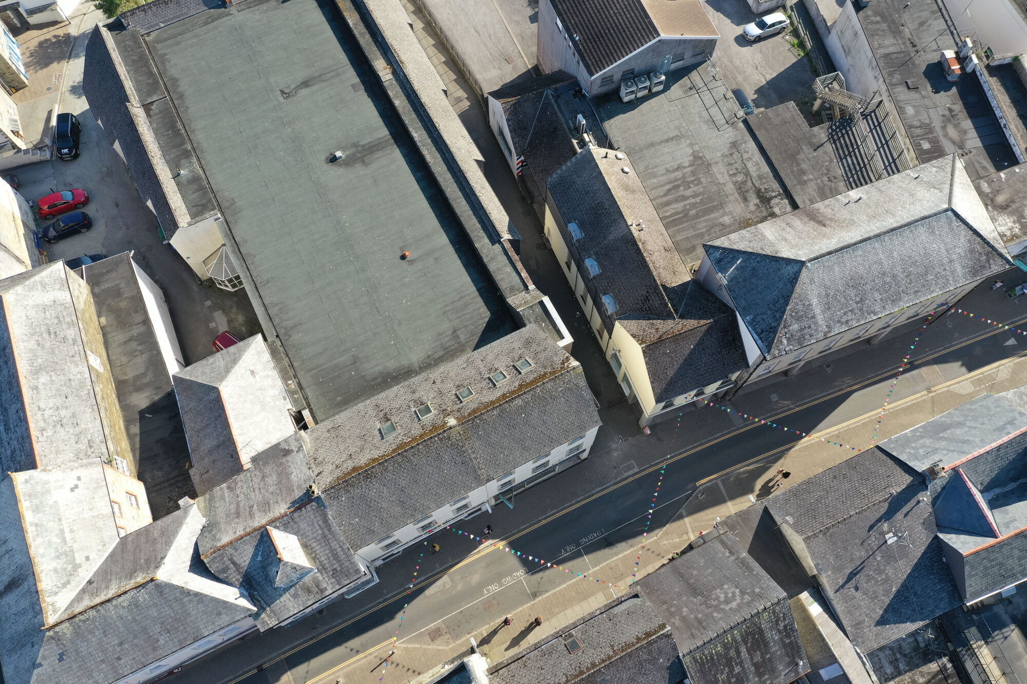 High-level angled drone view of Fore Street, Bodmin, showing the front and side of the property and its neighbouring roofs