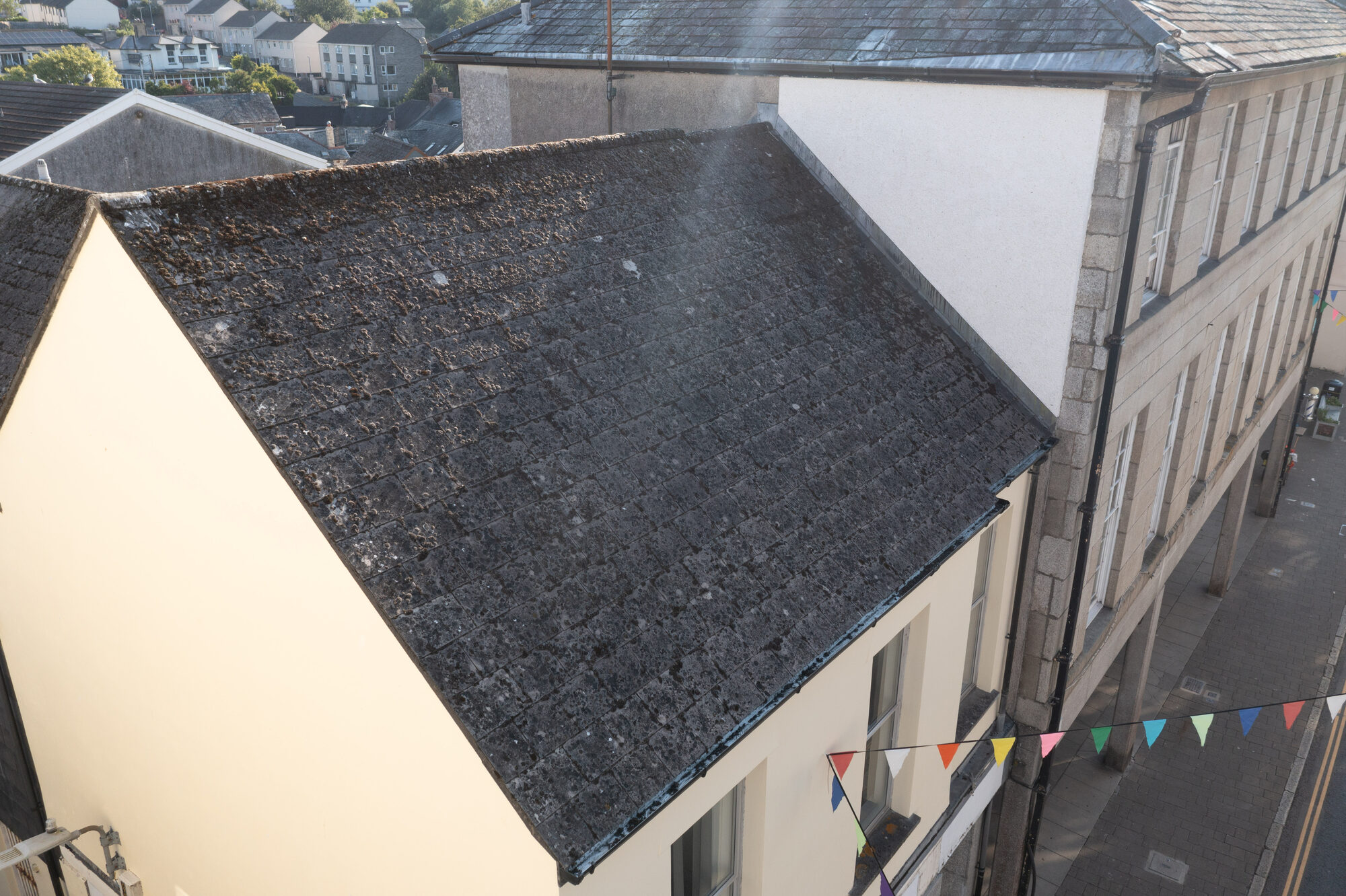 Drone photo of a slate roof and cream rendered building on Fore Street, Bodmin, Cornwall, with bunting across the street below