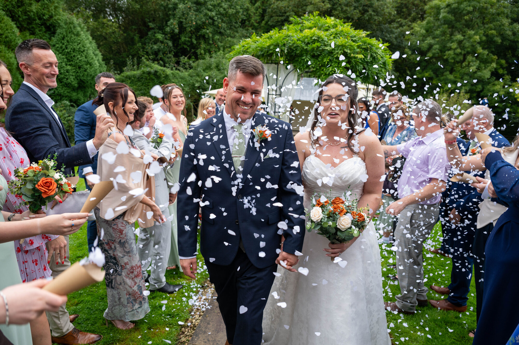 Bride and groom walking through confetti after outdoor ceremony