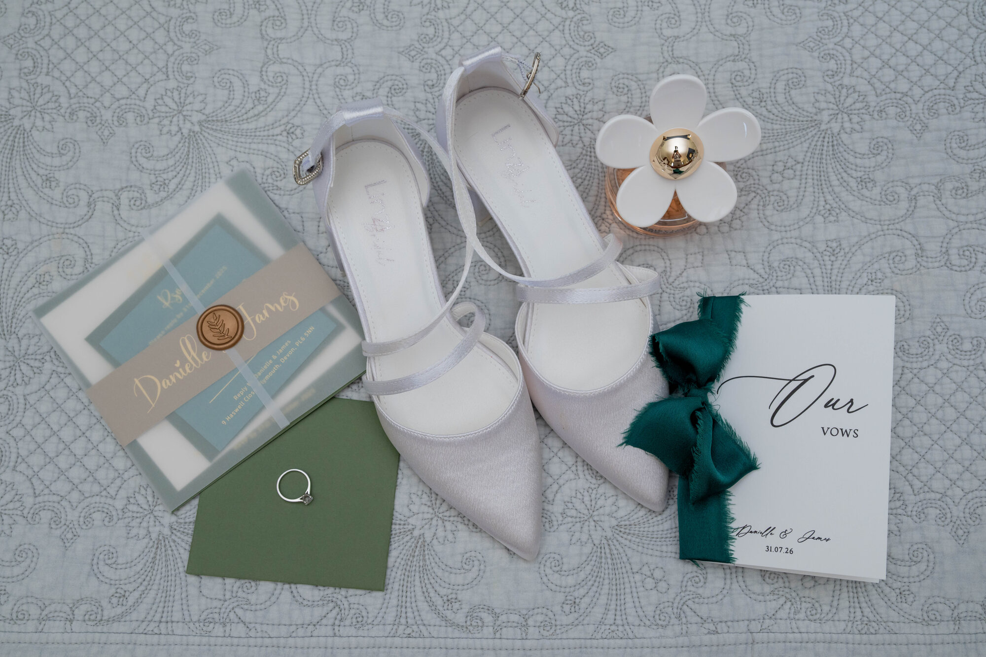 Flatlay featuring wedding rings, shoes, perfume and invitation for a Rockbeare Manor wedding