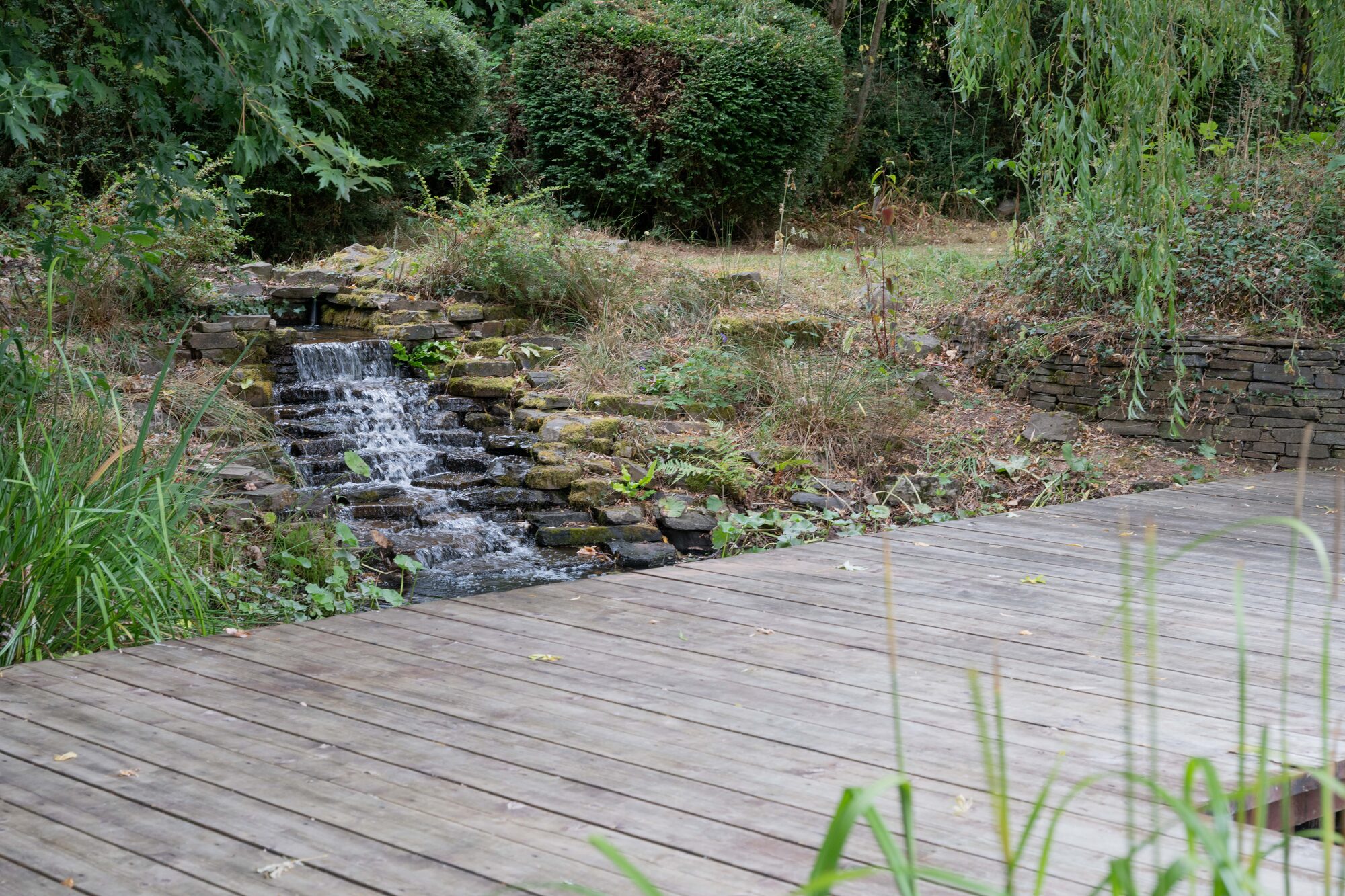 Wooden jetty and waterfall feature at Valleyside Barn