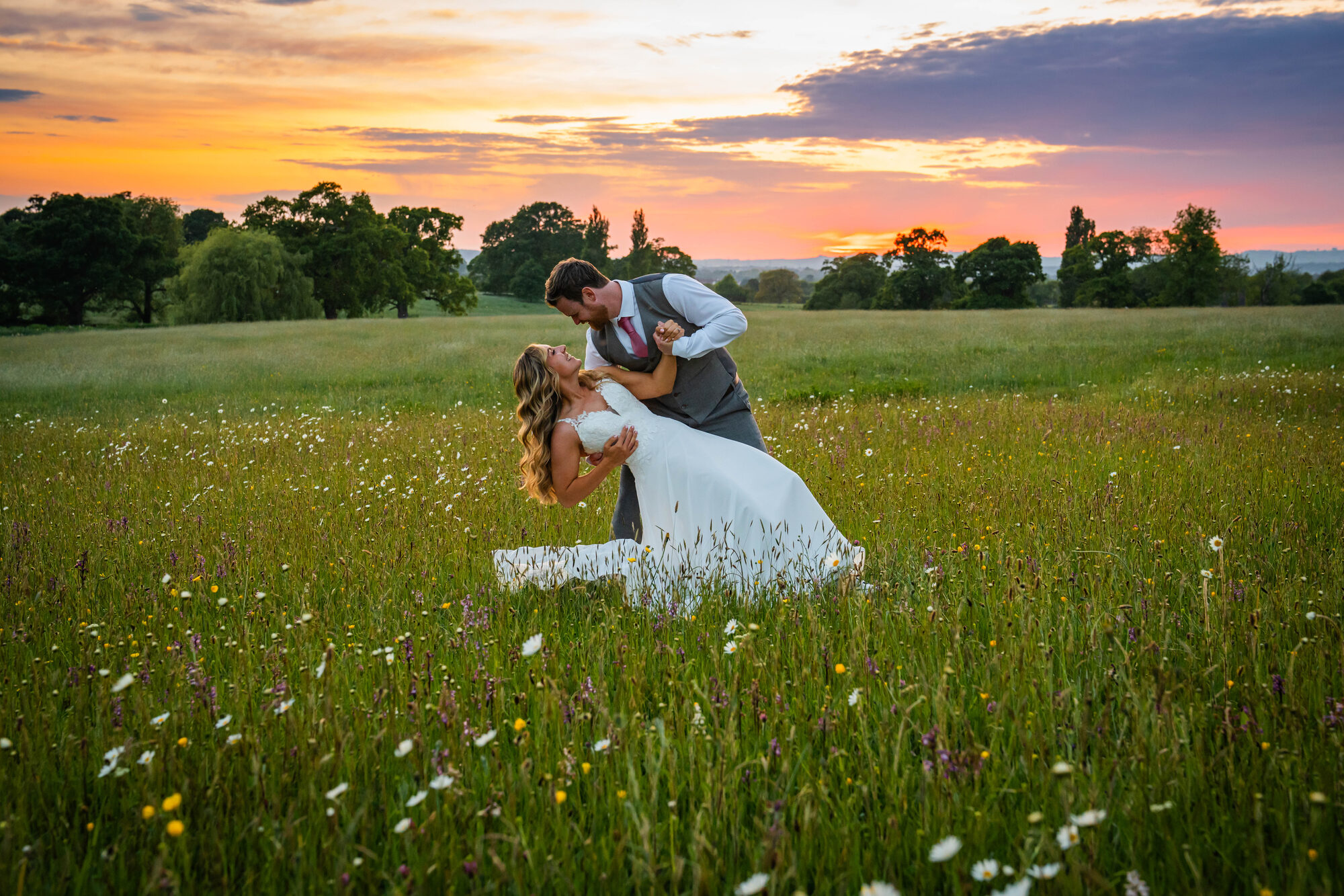 Bride and groom walking through meadow at Rockbeare Manor